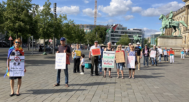 Teilnehmende des Schweigemarsches mit umgehängten Plakaten auf dem Schlossplatz Braunschweig